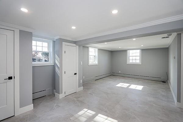 basement featuring ornamental molding, baseboard heating, a baseboard radiator, and baseboards