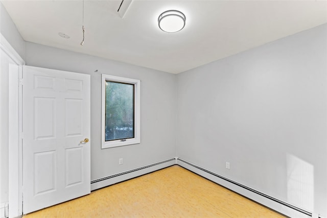 unfurnished room with a baseboard heating unit and wood-type flooring