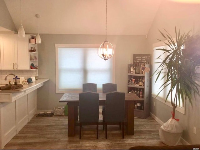 dining area featuring lofted ceiling, dark hardwood / wood-style floors, sink, and a chandelier