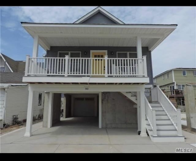 view of front of property featuring a carport, concrete driveway, covered porch, and stairway