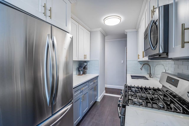 kitchen featuring sink, white cabinetry, ornamental molding, appliances with stainless steel finishes, and decorative backsplash