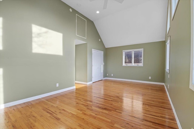 empty room featuring ceiling fan, high vaulted ceiling, and light wood-type flooring