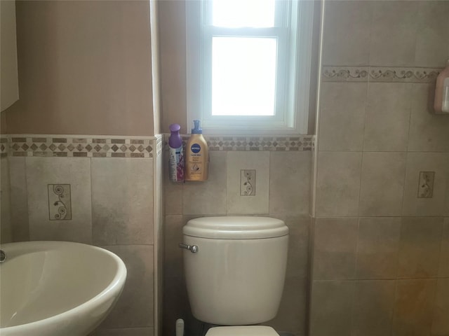 bathroom with tile walls, sink, and toilet