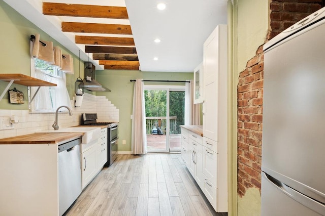 kitchen with backsplash, open shelves, light wood-style floors, wood counters, and stainless steel appliances