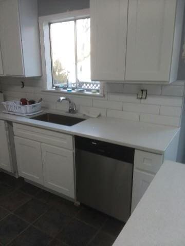 kitchen with sink, dishwasher, tasteful backsplash, white cabinets, and dark tile patterned flooring