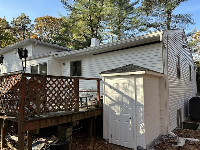 back of property with a deck and a shed