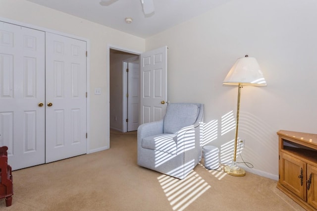 living area with light carpet and ceiling fan