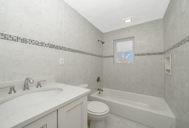 full bathroom with toilet, tile walls, vanity, tiled shower / bath combo, and tile patterned flooring