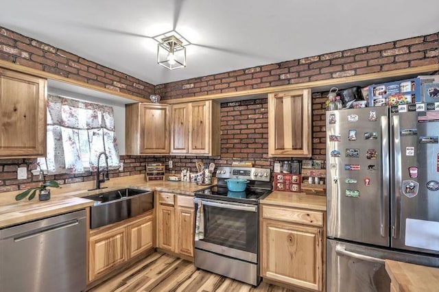 kitchen with brick wall, stainless steel appliances, sink, and butcher block countertops