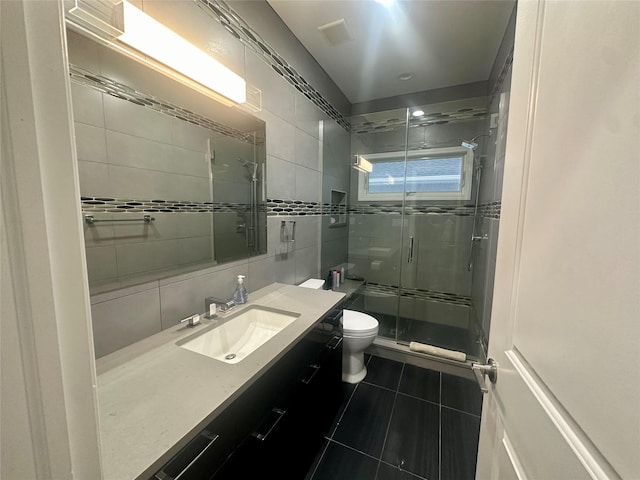 bathroom with walk in shower, tile patterned floors, toilet, tile walls, and vanity