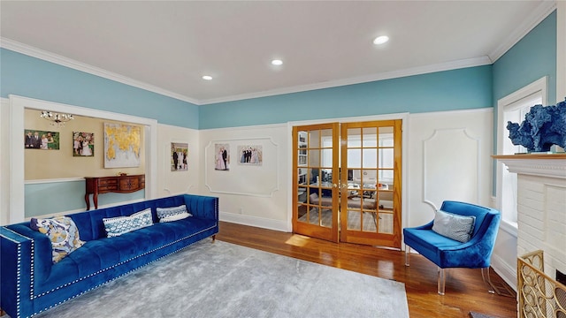 living room featuring french doors, crown molding, a brick fireplace, and hardwood / wood-style flooring