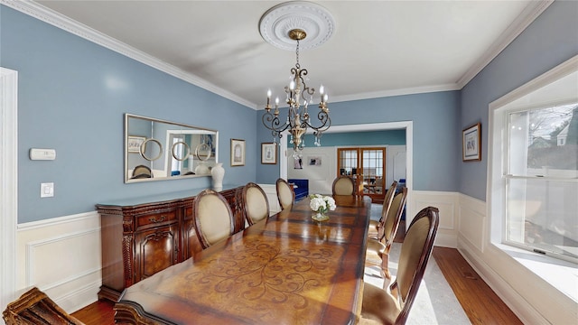 dining space with crown molding, wood-type flooring, and a notable chandelier