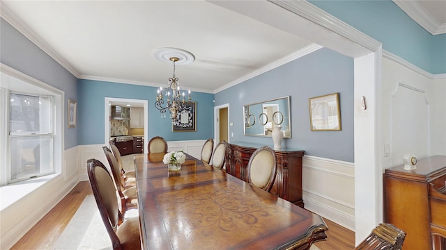 dining area with an inviting chandelier, crown molding, and light hardwood / wood-style floors