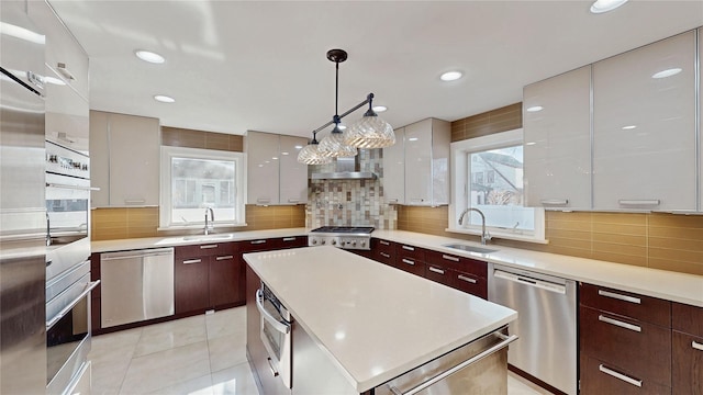 kitchen featuring sink, decorative backsplash, stainless steel appliances, and hanging light fixtures