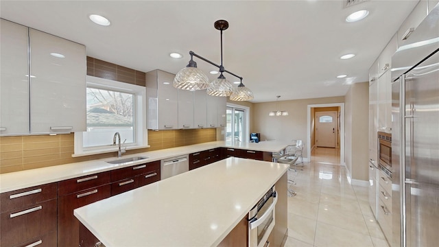 kitchen featuring a kitchen island, tasteful backsplash, sink, hanging light fixtures, and stainless steel appliances