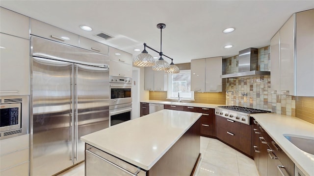 kitchen featuring wall chimney range hood, dark brown cabinets, built in appliances, and backsplash