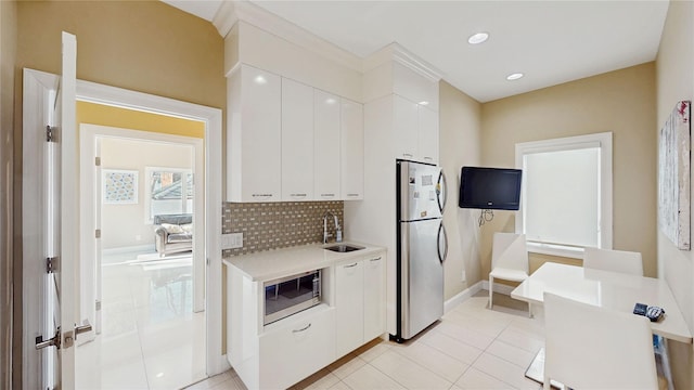 kitchen with sink, light tile patterned floors, stainless steel appliances, white cabinets, and decorative backsplash