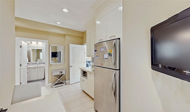 kitchen with white cabinetry, stainless steel fridge, and light tile patterned floors