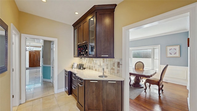 kitchen featuring backsplash, dark brown cabinets, and light hardwood / wood-style floors