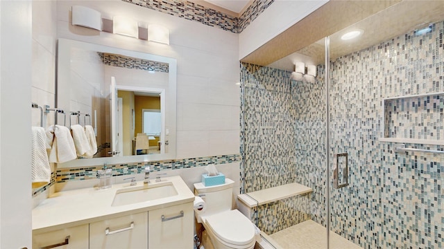 bathroom with tile walls, tasteful backsplash, vanity, a shower with shower door, and toilet