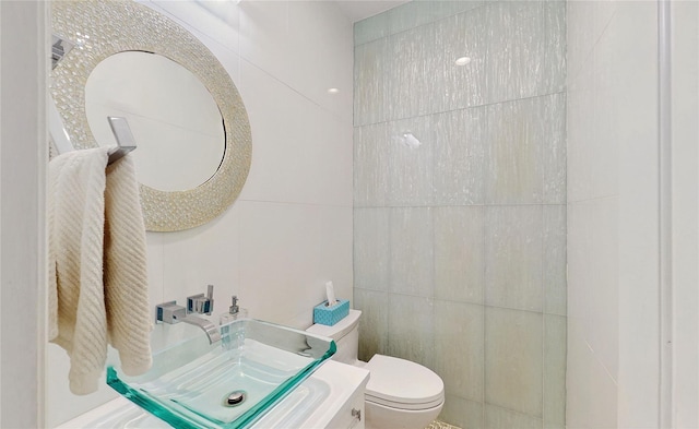 bathroom featuring vanity, tile walls, and toilet