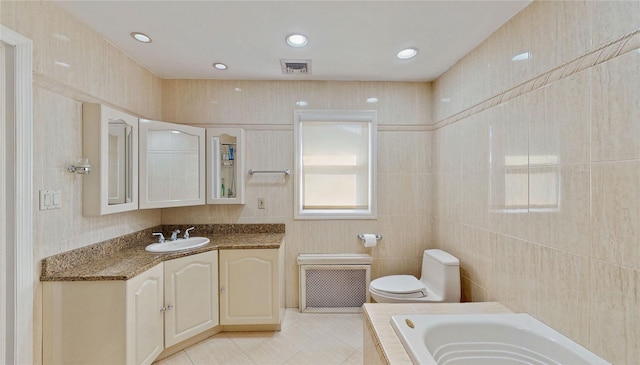 bathroom with tile patterned floors, toilet, tile walls, vanity, and a bath