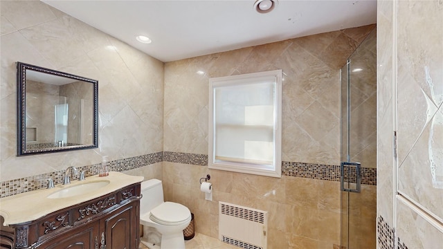 bathroom with tile walls, radiator heating unit, vanity, toilet, and walk in shower