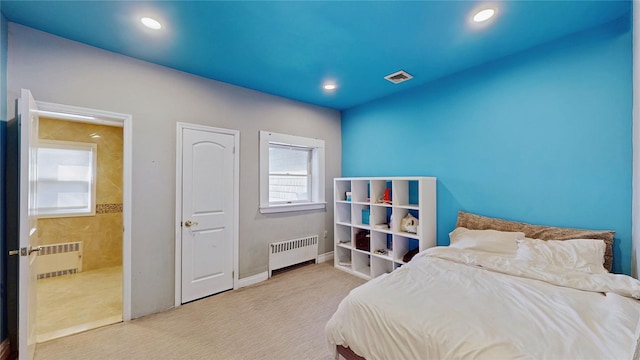 bedroom with light carpet and radiator heating unit