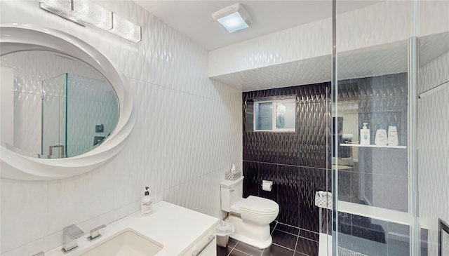 bathroom with a shower with shower door, tile walls, vanity, toilet, and tile patterned floors