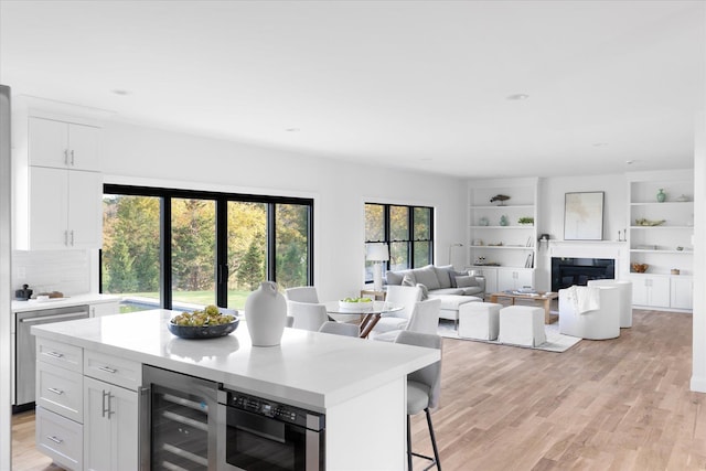 kitchen featuring wine cooler, white cabinets, a kitchen breakfast bar, and light hardwood / wood-style flooring