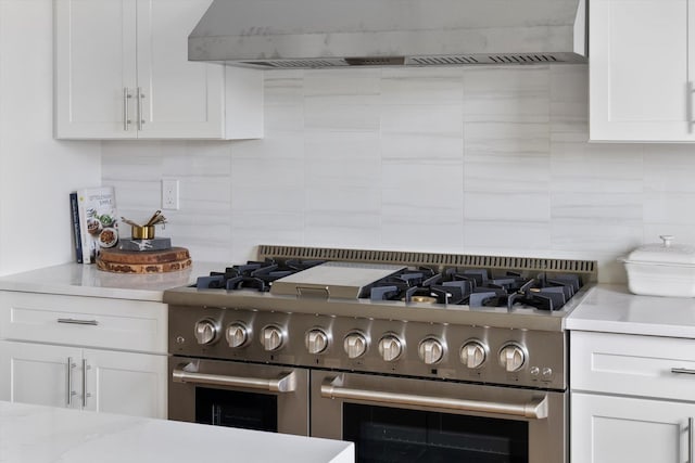 kitchen featuring white cabinetry, double oven range, backsplash, and custom exhaust hood