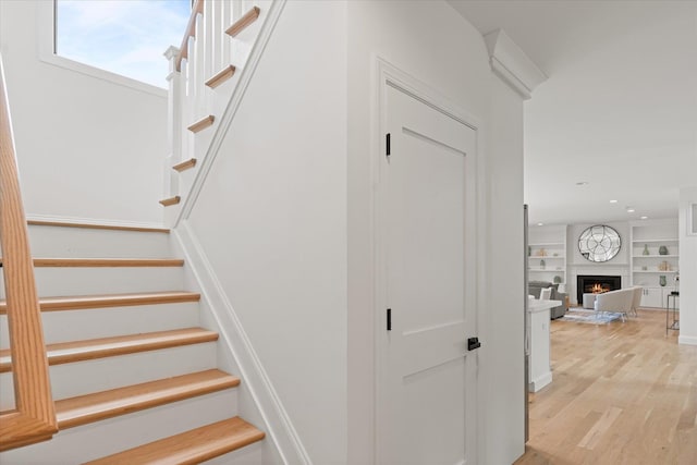 stairway with hardwood / wood-style floors and built in shelves