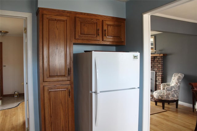 kitchen featuring white refrigerator, crown molding, and light hardwood / wood-style flooring