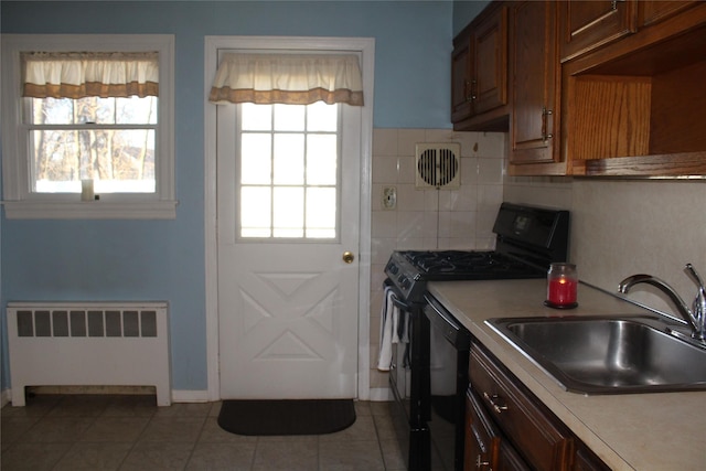 kitchen featuring plenty of natural light, sink, radiator heating unit, and black appliances