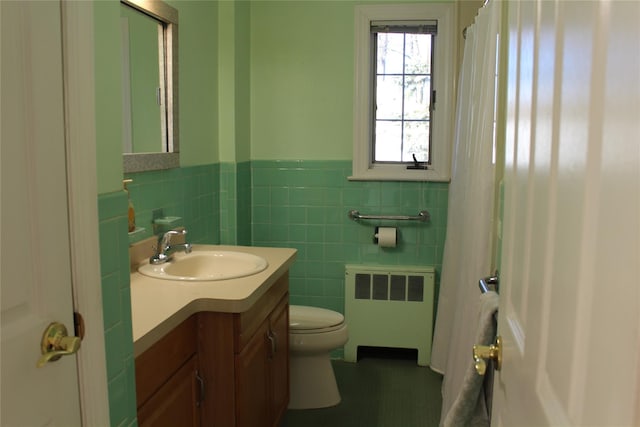 bathroom featuring radiator heating unit, toilet, vanity, and tile walls