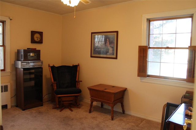 living area with crown molding, radiator, and light carpet