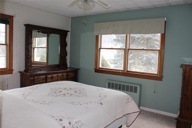 bedroom with multiple windows, carpet floors, and radiator heating unit