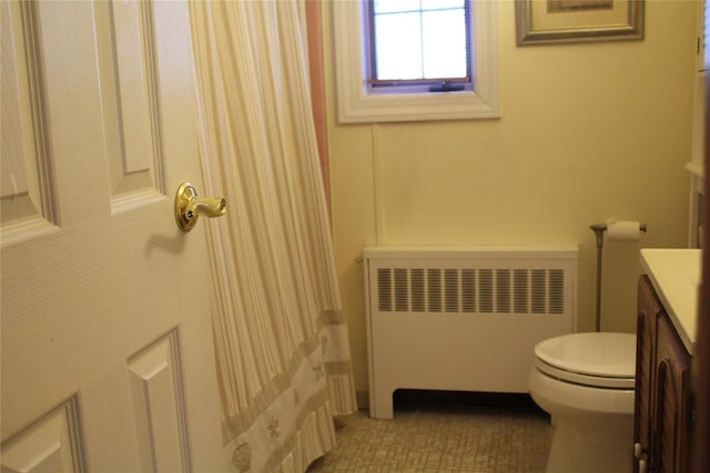 bathroom featuring vanity, toilet, radiator, and tile patterned flooring