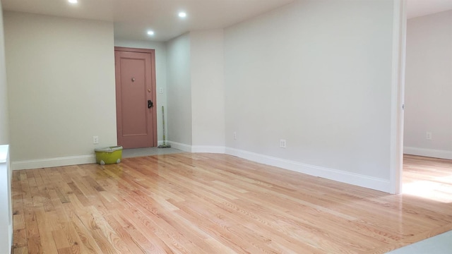 empty room with baseboards, recessed lighting, and light wood-style floors