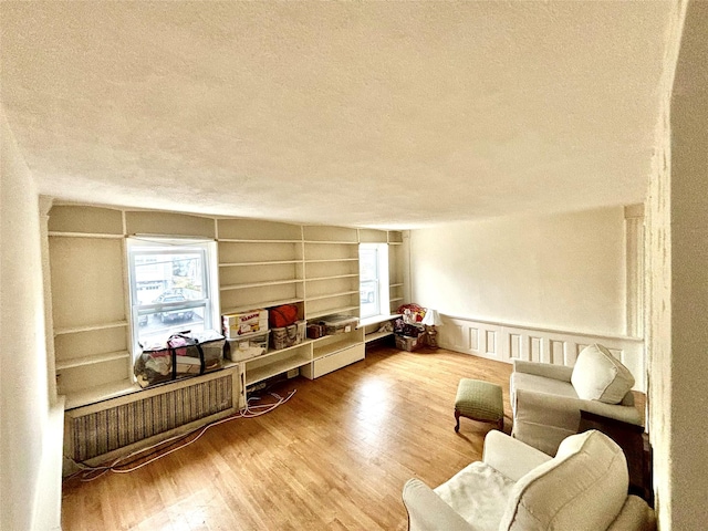 living area featuring wood-type flooring, built in features, and a textured ceiling