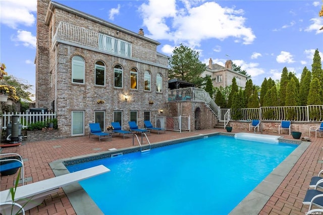 view of swimming pool with a patio area and a diving board