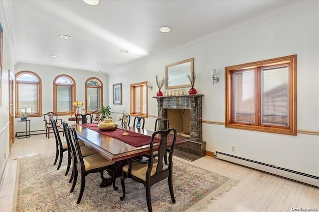 dining area with a baseboard heating unit, crown molding, and light hardwood / wood-style floors