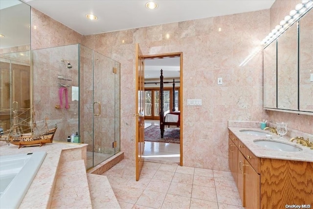 bathroom with tile patterned floors, shower with separate bathtub, vanity, and tile walls