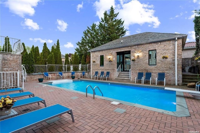 view of swimming pool with a diving board and a patio