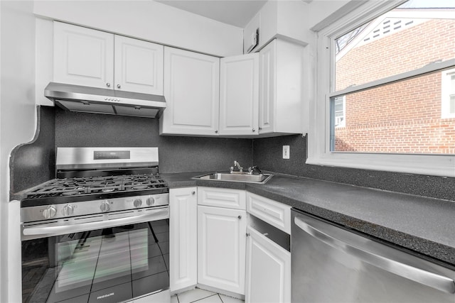 kitchen with dark countertops, a sink, stainless steel appliances, under cabinet range hood, and backsplash