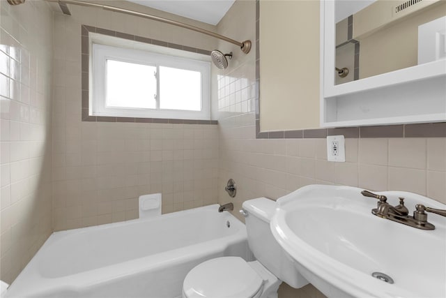 bathroom featuring tile walls, a sink, shower / bathing tub combination, and toilet