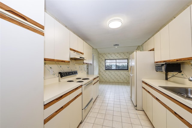 kitchen featuring tasteful backsplash, white electric stove, white cabinets, light tile patterned floors, and sink