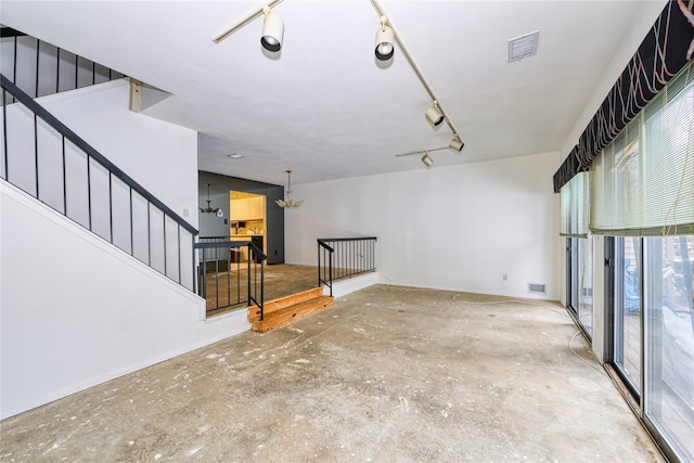 interior space with concrete flooring, a chandelier, and rail lighting