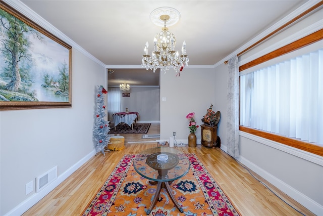 interior space featuring hardwood / wood-style flooring, crown molding, and an inviting chandelier