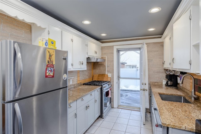 kitchen with extractor fan, appliances with stainless steel finishes, white cabinetry, sink, and light stone countertops